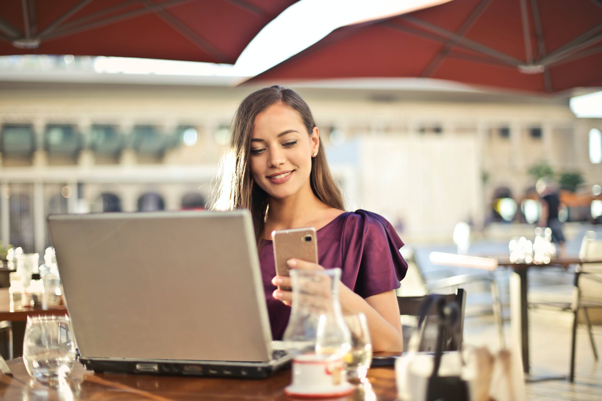 Vrouw op terras met laptop en telefoon
